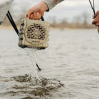 Person holding a Turtlebox Cub speaker over water.