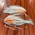 Two fly fishing lures on a wooden surface