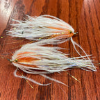 Two fly fishing lures on a wooden surface