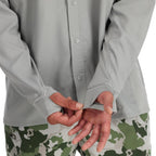 Person wearing a light gray Back view of man wearing a Simms MEN's Intruder Bicomp Fishing Shirt and camouflage pants on a white background