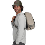 Man wearing a beige backpack on a white background