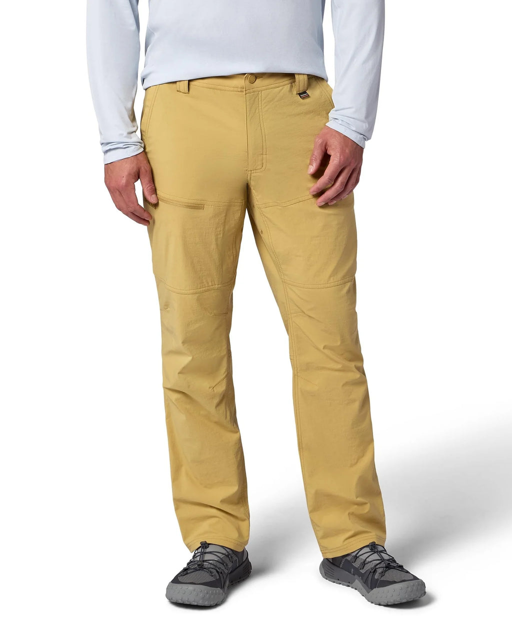 Person wearing Simms Guide Beige pants with a brand logo on a white background