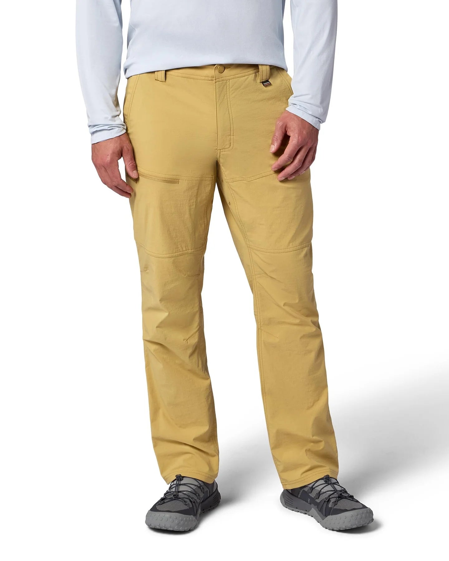 Person wearing Simms Guide Beige pants with a brand logo on a white background