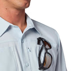 Man wearing a light blue shirt with sunglasses hanging from the collar.