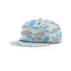 A camouflage baseball cap with a light gray, blue, and mint green pattern, featuring a front patch that reads 'CHAGRIN RIVER OUTFITTERS' with a fish illustration. The cap is resting on a polished wooden surface.