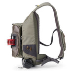 Green and gray Orvis Guide Sling Pack with fishing gear on a white background