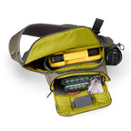 Open green and gray Orvis Guide Sling Pack with compartments on a white background