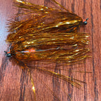 Fishing fly with gold and black details on a wooden surface