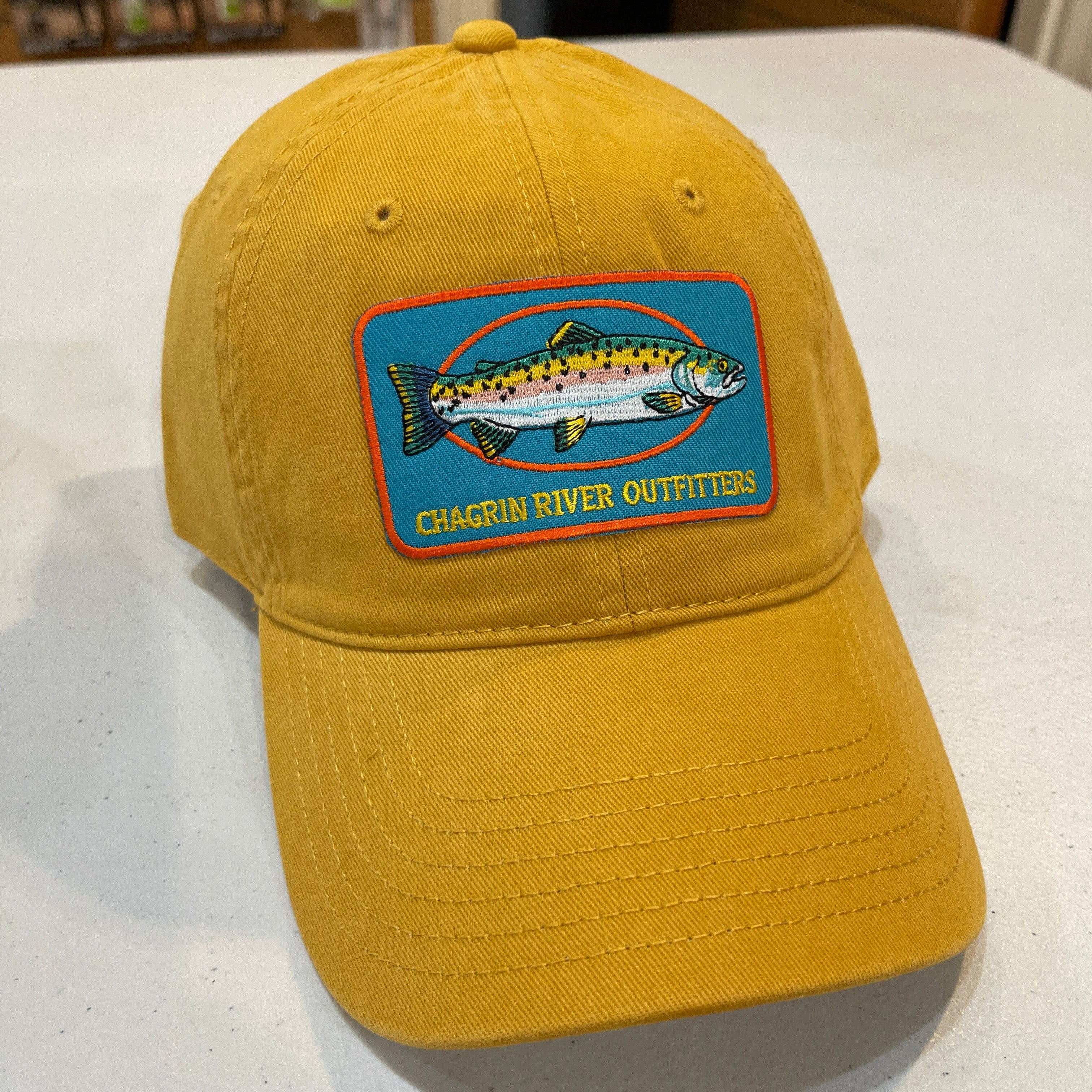 Yellow cap with a fish logo patch on a white surface