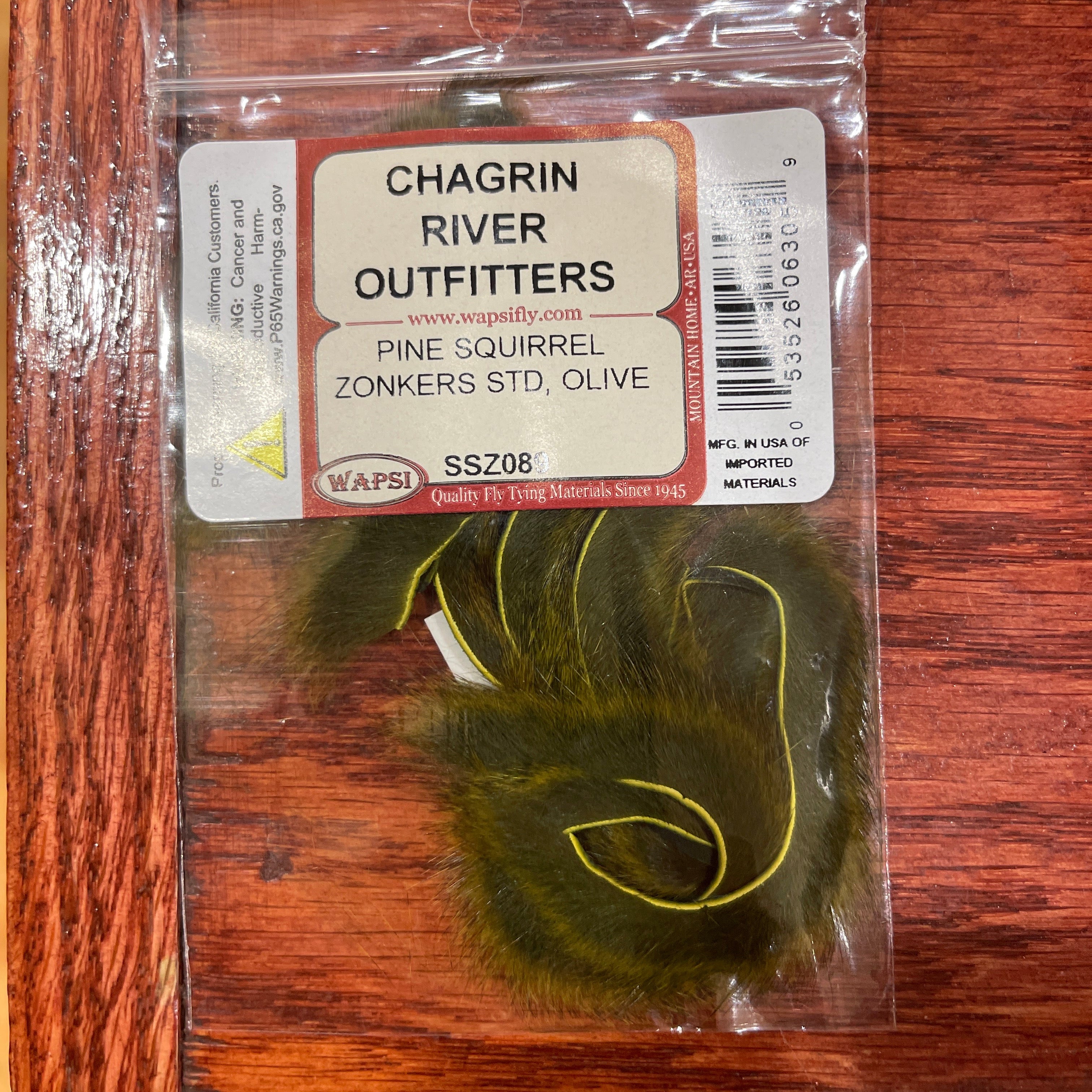Packaged zonker lure with Chagrin River Outfitters label on a wooden surface