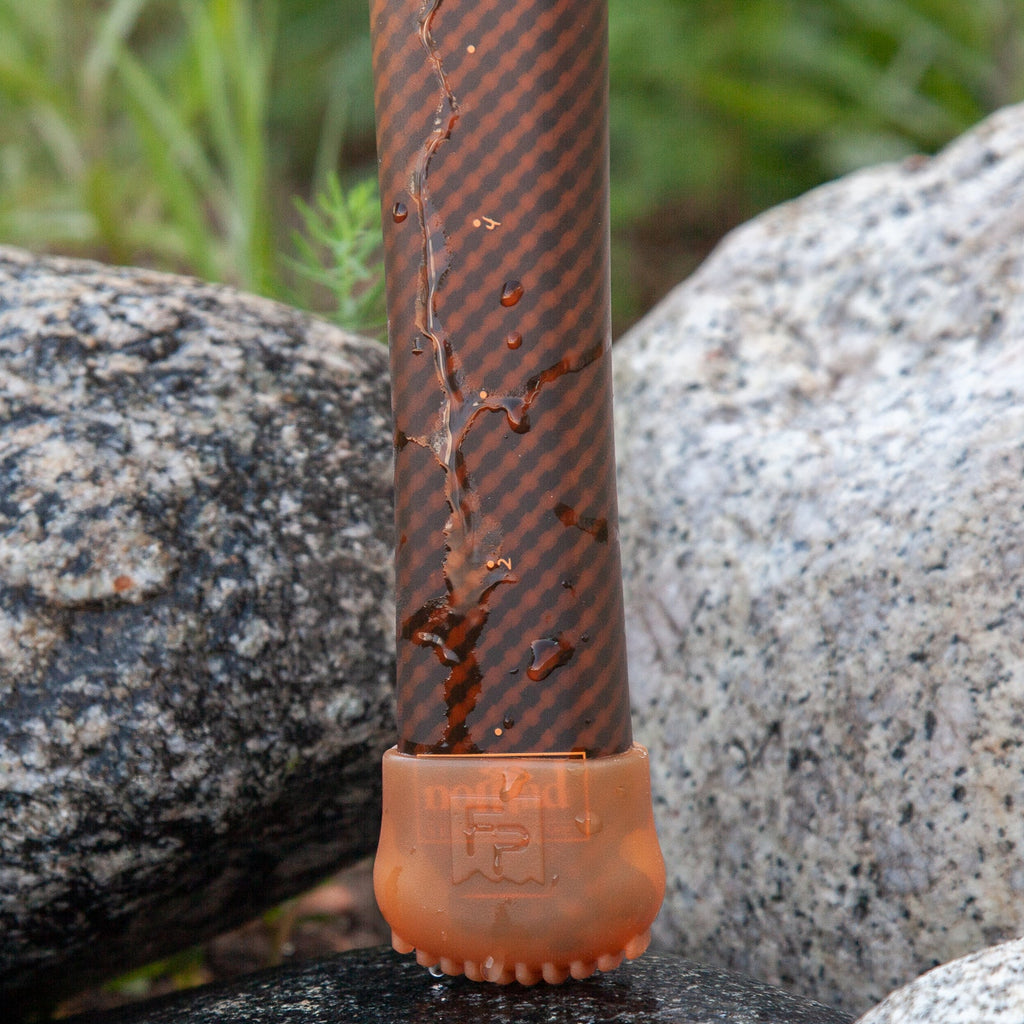 Carbon fiber landing net with orange cap on rocks.