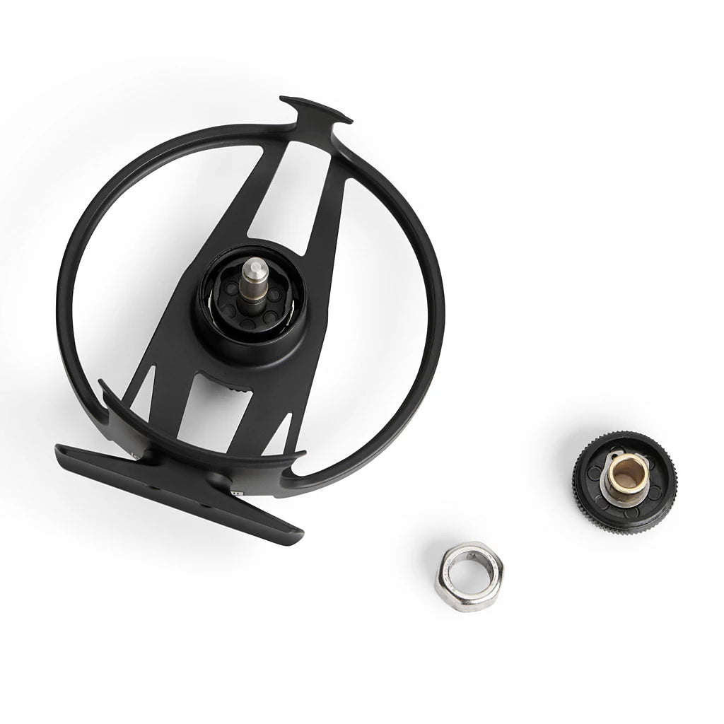 Black metal fly fishing reel with additional components on a white background