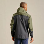 Person wearing a green and black Orvis MEN's PRO Fishing Jacket on a beige background