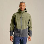 Man wearing a green and gray Orvis MEN's PRO Fishing Jacket with 'Orvis' branding on a beige background