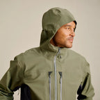Man wearing a green Orvis MEN's PRO Fishing Jacket against a beige background