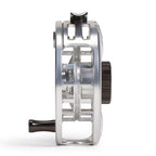 A close-up side profile of an Orvis Hydros metallic silver fly fishing reel with black handle and knob details, set against a clean white background.