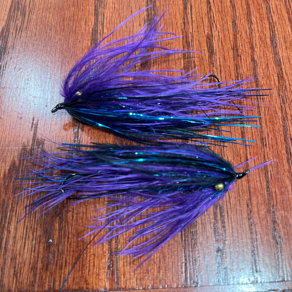 Two purple and black fishing lures on a wooden surface