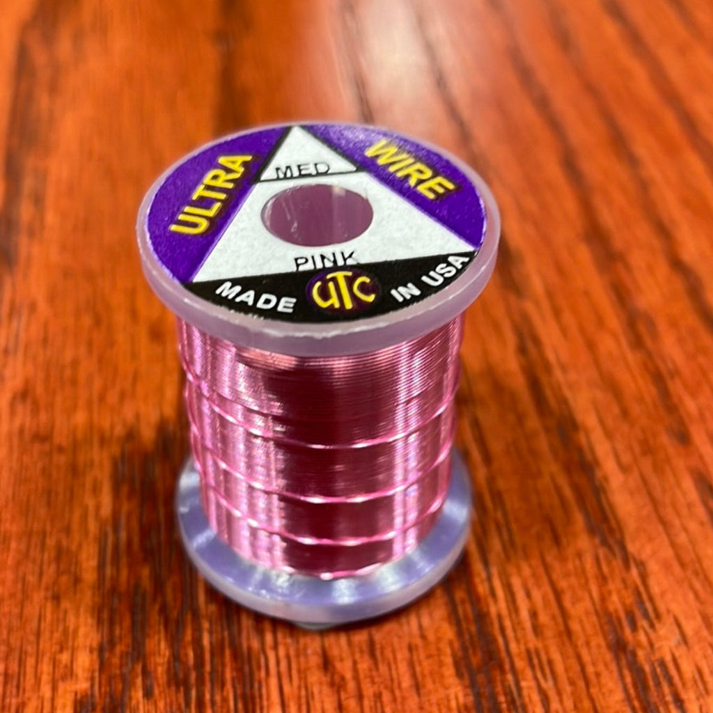 Spool of pink Wapsi Ultra Wire UTC with a label on a wooden surface