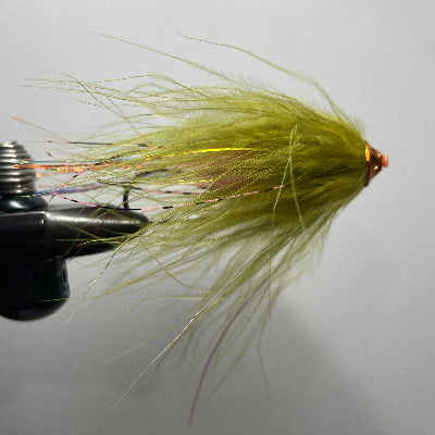 A close-up of a handmade tube fly fishing fly with a bright chartreuse yellow-green body and wispy fibers, held in a black fly tying vise against a neutral gray background.