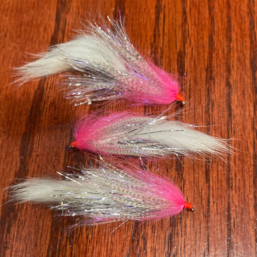 Three fishing lures with pink and white patterns on a wooden surface
