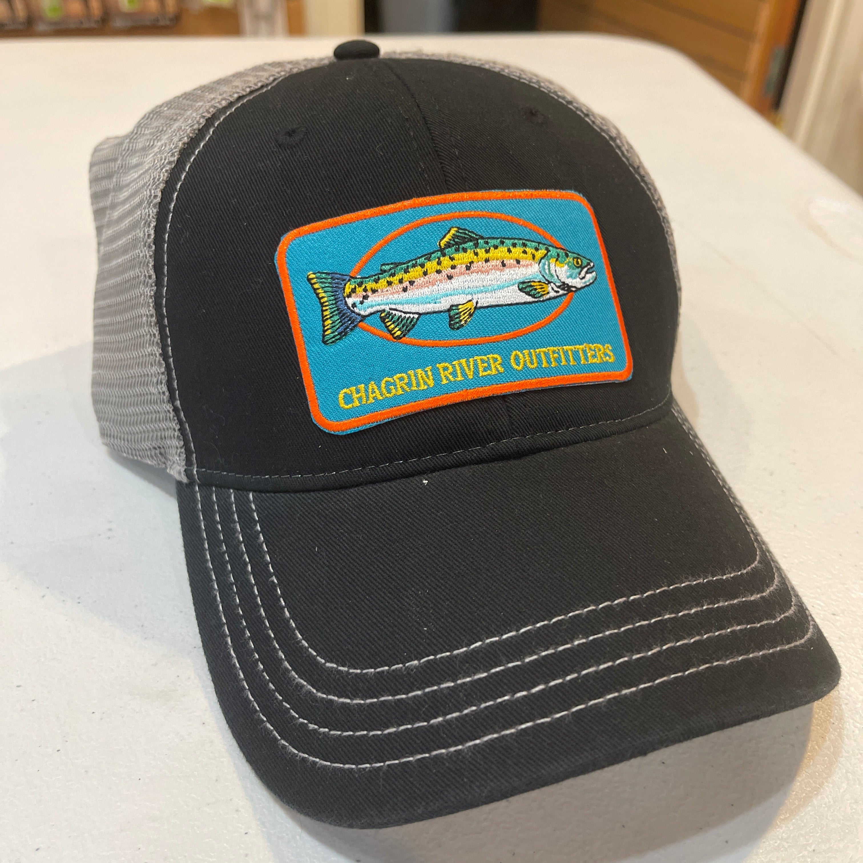 Black and gray cap with a fish logo and 'Chagrin River Outfitters' text on a white surface.