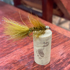Fishing fly with a tag on a wooden surface