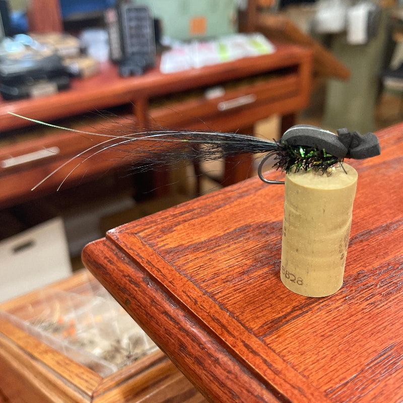 Cork with a small insect attached to it on a wooden surface