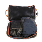 Open travel bag with black interior and orange trim, containing a dark blue garment and a black item.