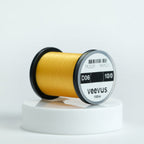 Spool of yellow veevus fly-tying thread on a white background