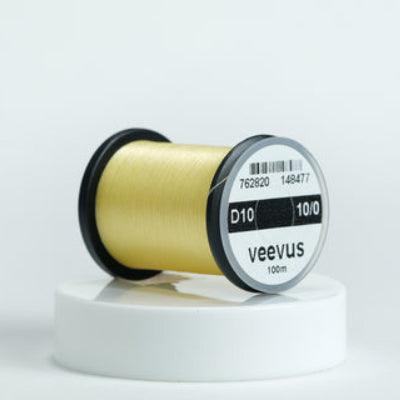 Spool of cream veevus fly-tying thread on a white background