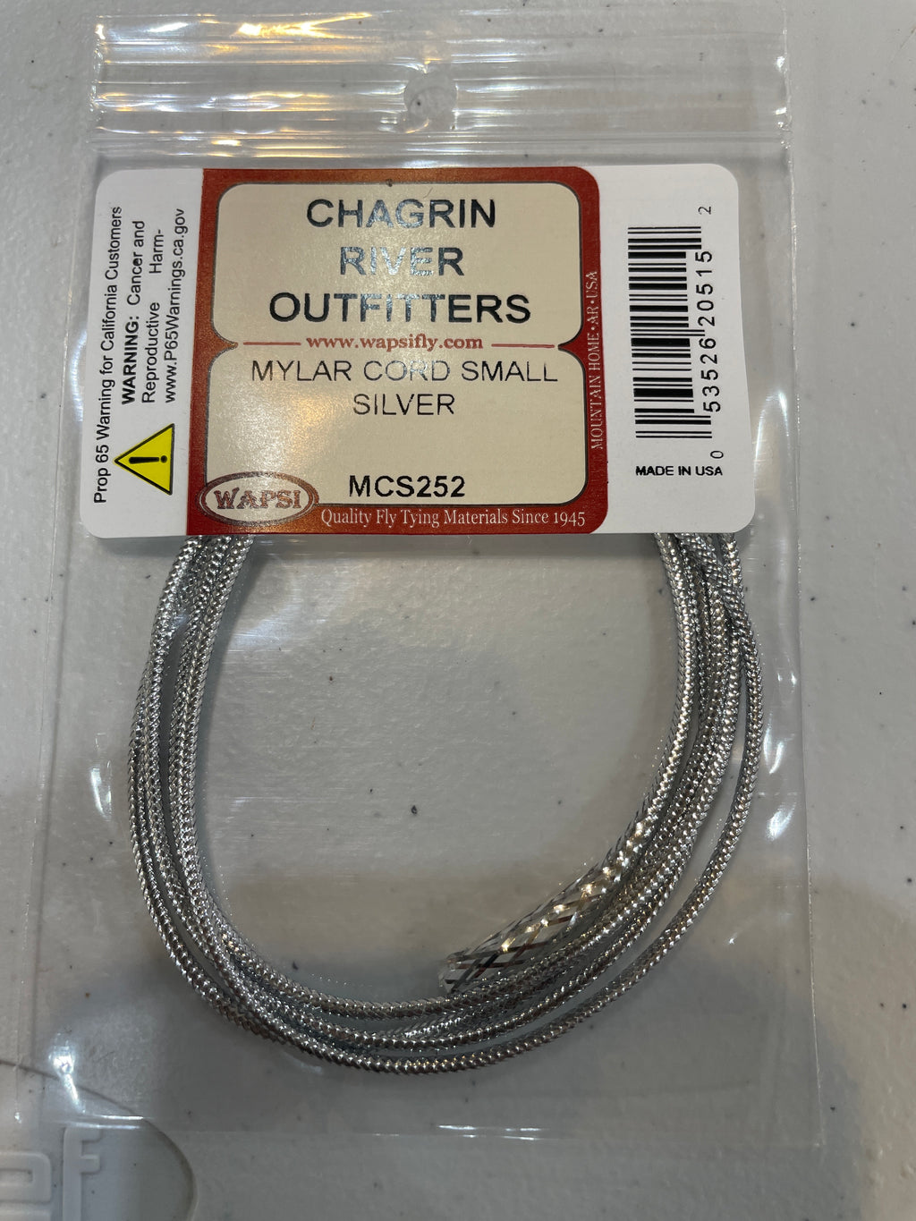 Packaged Wapsi Mylar Cord in silver color, intended for use in fly tying, with Chagrin River Outfitters branding visible.