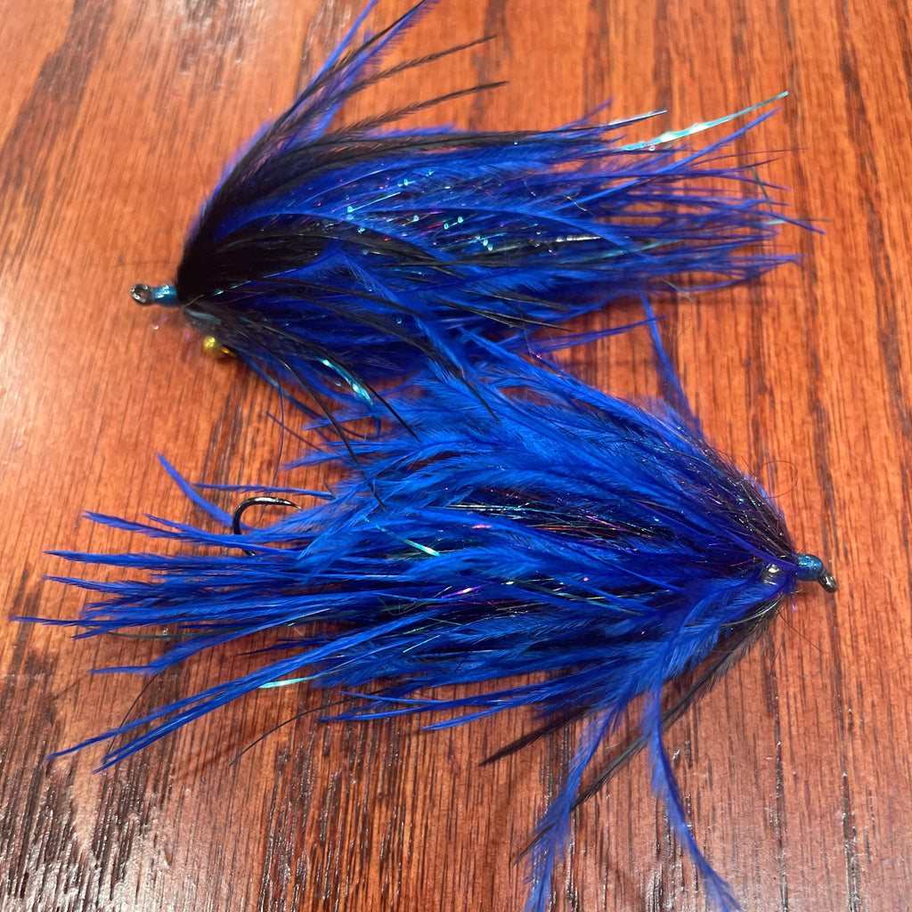 Two blue and black fishing lures on a wooden surface