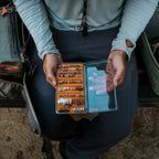 Person holding a Fishpond fly box with flies in an outdoor setting