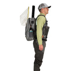 Angler wearing a Gray Simms Dry Creek Z Backpack with orange 'Simms' logo on a white background
