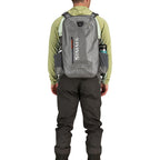 Angler wearing a Gray Simms Dry Creek Z Backpack with orange 'Simms' logo on a white background