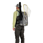 Angler wearing a Gray Simms Dry Creek Z Backpack with orange 'Simms' logo on a white background