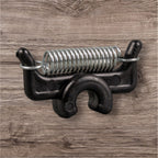 A black PEAK Material Clip with a straight coil design, attached to a wooden surface.