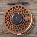 Orvis Battenkill Disc Fly Reel with a copper body and the brand name visible, placed on a wooden surface.
