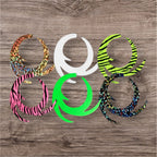 A collection of synthetic fishing lures in various colors and patterns laid out on a wooden surface.