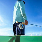 Person holding a fishing rod with a blue sky and water background