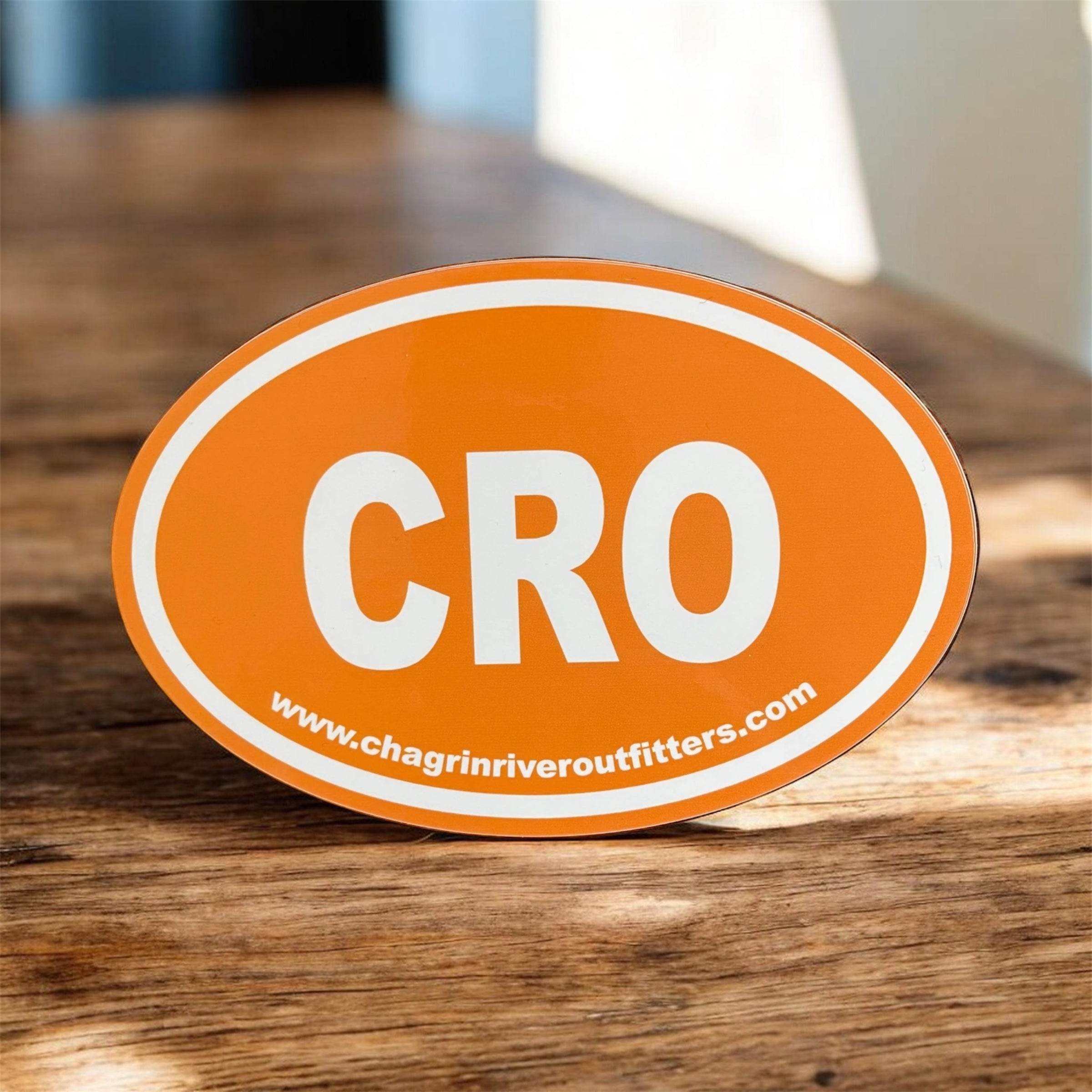 Orange oval sticker with 'CRO' and website URL on a wooden surface