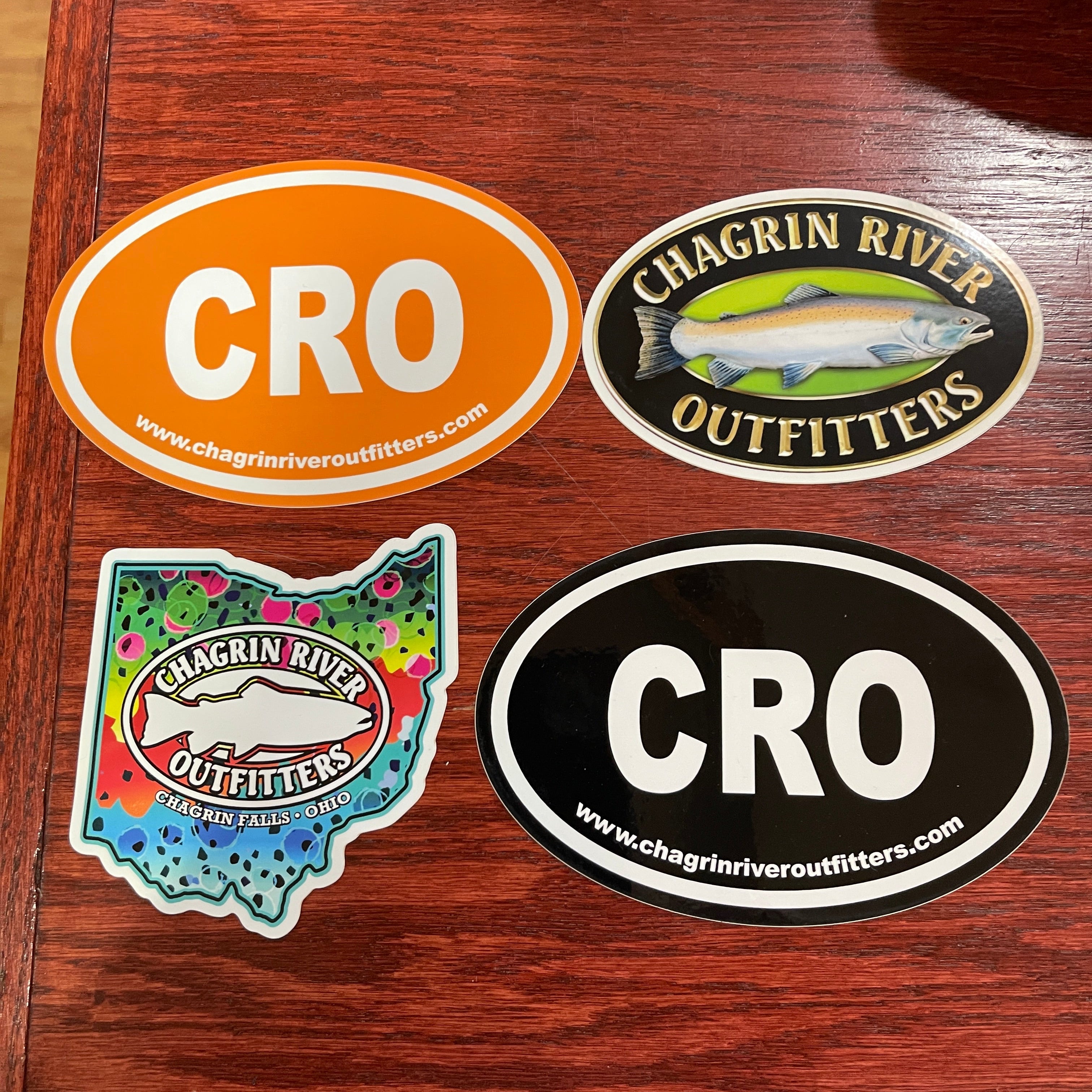 Four Chagrin River Outfitters stickers on a wooden surface.