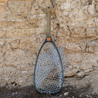 Fishpond fishing net with a clear net against a textured stone wall