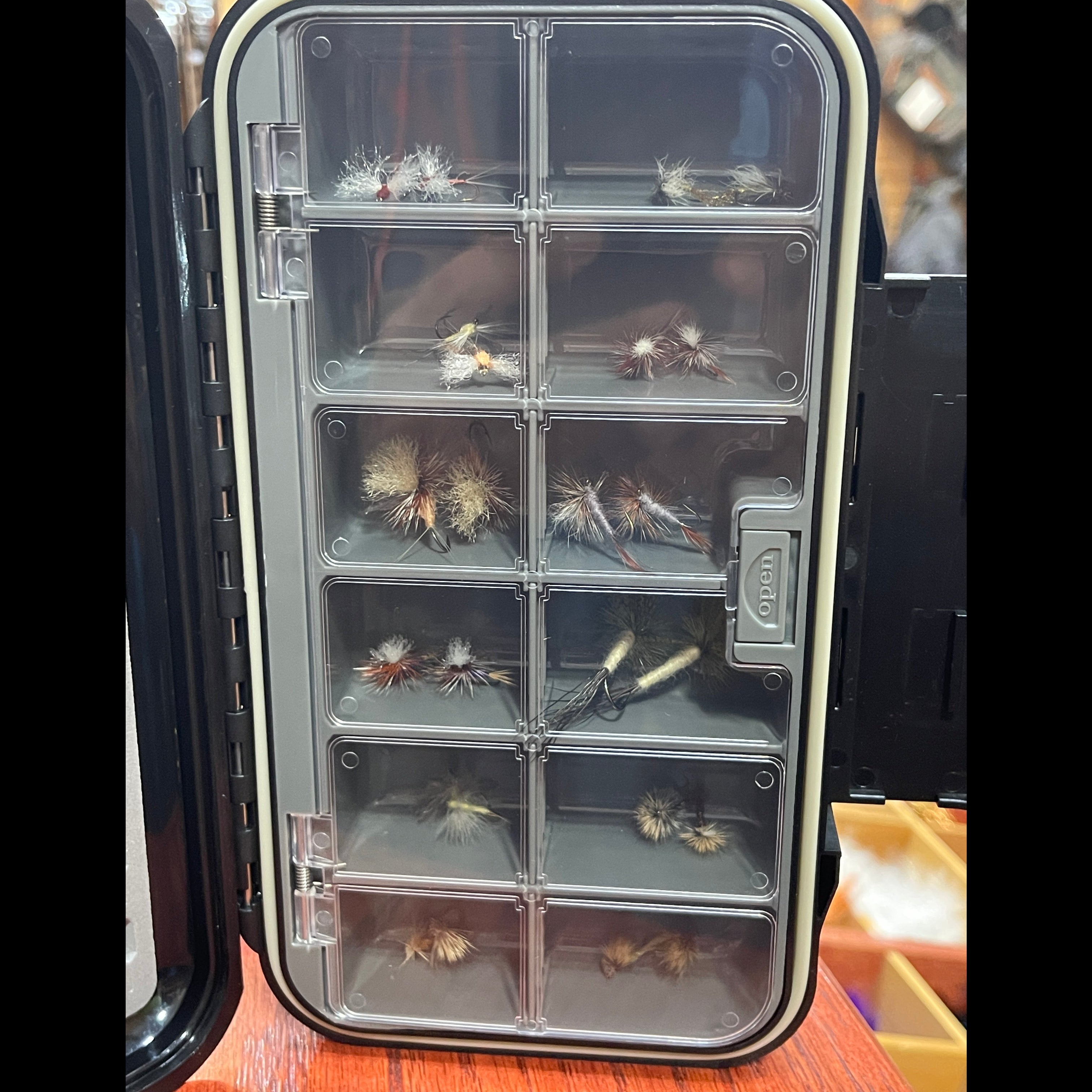 Clear fly fishing fly box with various dry fly patterns inside.