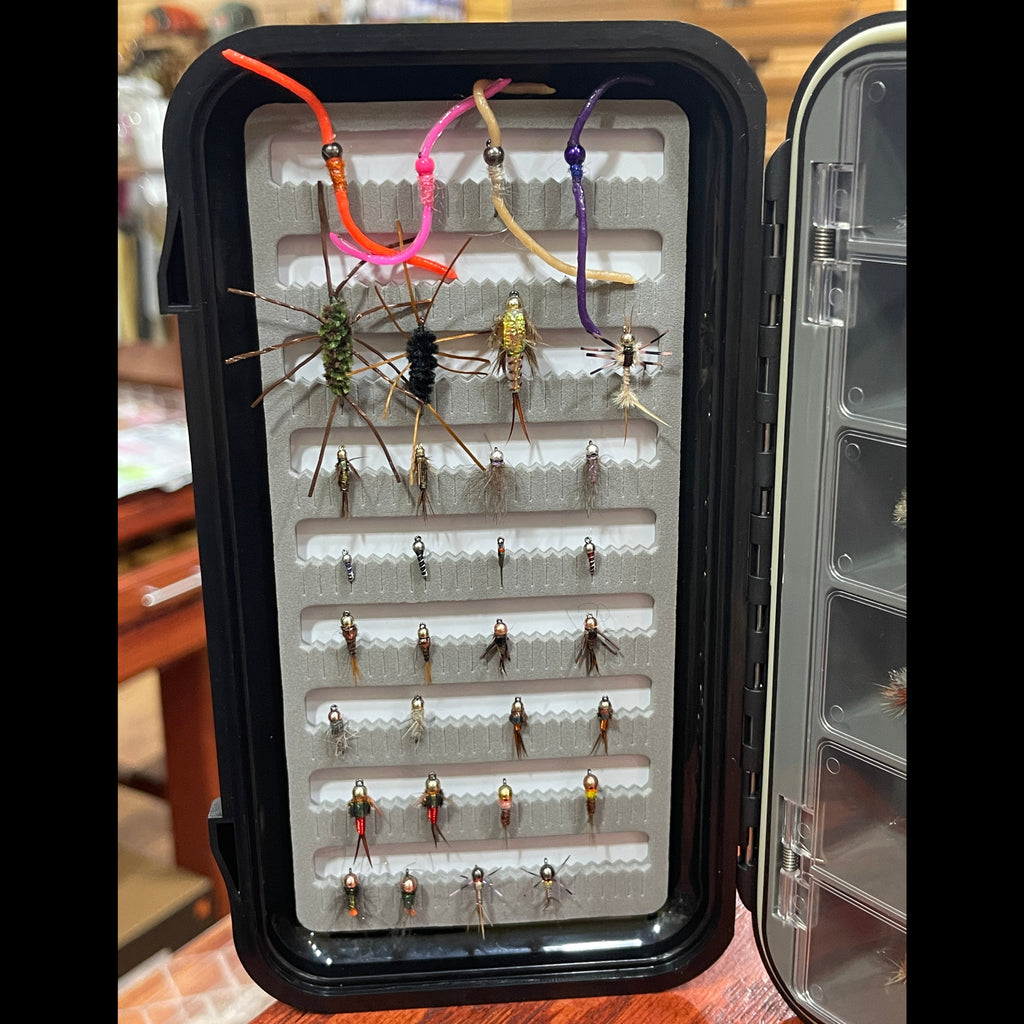 Fishing fly assortment in a black case on a wooden surface