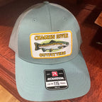 A light gray trucker-style cap with a large 'Chagrin River Outfitters' fish patch on the front and a 'Richardson' size 115 sticker on the brim, resting on a dark wooden surface.