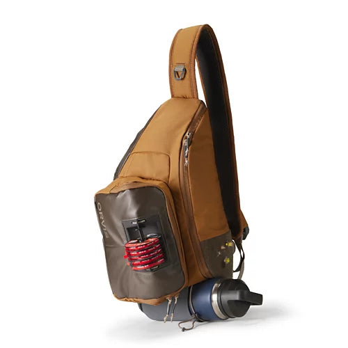 A brown and dark gray sling backpack with a side pocket holding a red striped item, shown on a white background with a blue water bottle tucked underneath.
