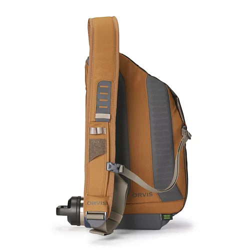 An orange-brown and gray Orvis sling backpack shown from the side profile on a white background, with a black water bottle attached to the shoulder strap.