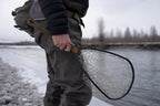 Person holding a fishing net by a river