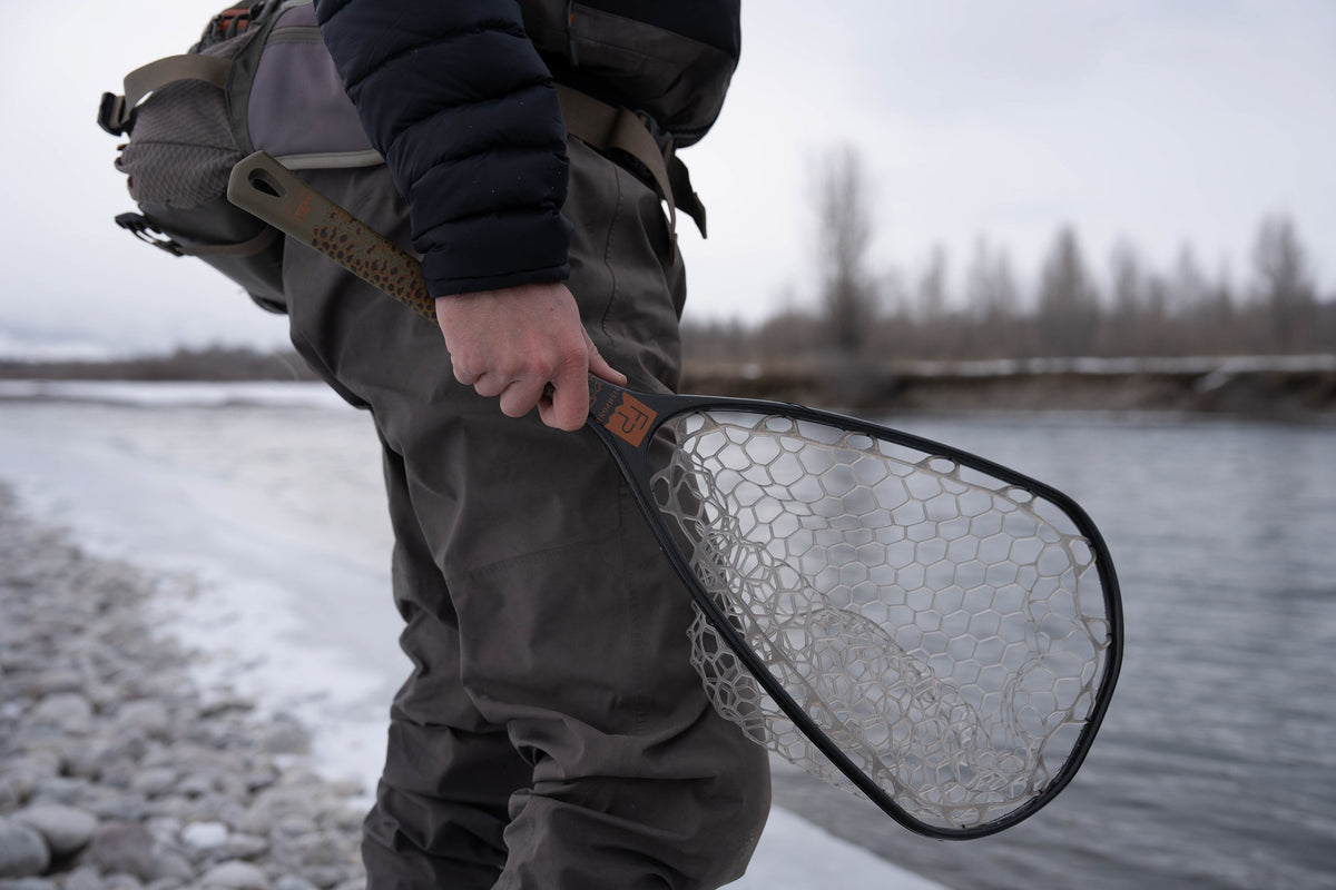 Person holding a fishing net by a river